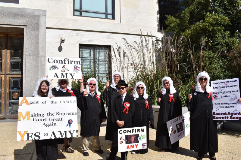 The group of singers will wear judge's white wigs, judge robes and sunglasses, as well as hold signs and wave gavels to assist lead singer 14-year-old Nick Liberty. They will be singing to the tune of "Secret Agent Man" from 1966, the group has different words for the song and their own refrain: Amy Coney Barrett Amy Coney Barrett They're giving us a justice And taking away the shame