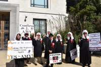 The group of singers will wear judge's white wigs, judge robes and sunglasses, as well as hold signs and wave gavels to assist lead singer 14-year-old Nick Liberty. They will be singing to the tune of "Secret Agent Man" from 1966, the group has different words for the song and their own refrain:

Amy Coney Barrett
Amy Coney Barrett
They're giving us a justice
And taking away the shame